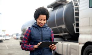 trucker looking at tablet in front of a truck