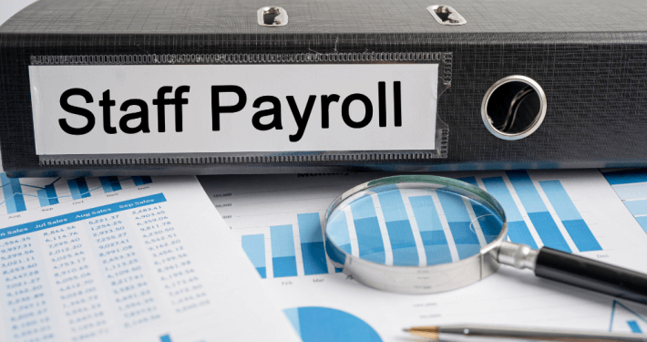 binder labeled "staff payroll" sitting on top of financial charts