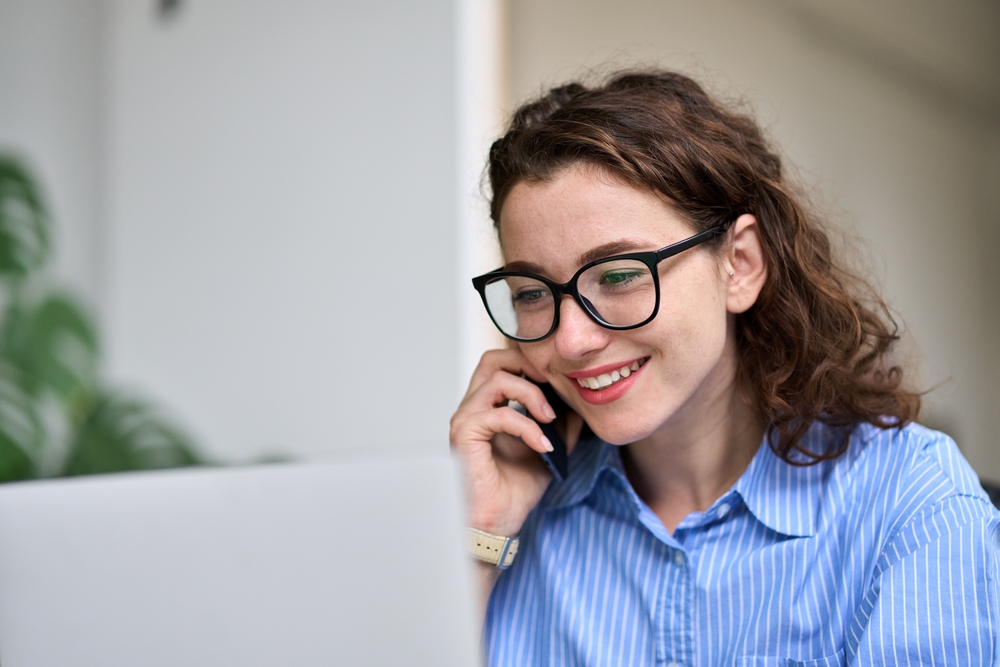 young female business owner on phone looking at laptop