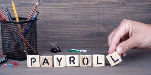 wooden blocks on a desk spelling out payroll